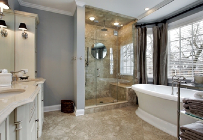 Bathroom with white free-standing tub and tiled walk-in shower with seat